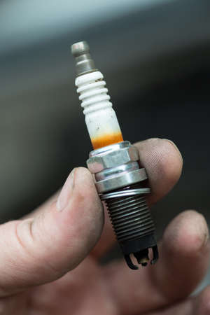 A worn spark plug in male hand