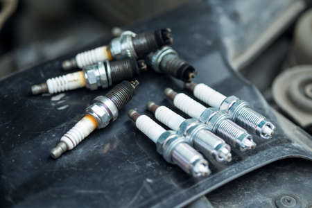 Worn and new spark plugs on the engineの写真素材