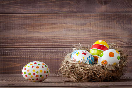 Colorful easter eggs in a nest on wooden boards の写真素材