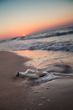 Bottle in the sand by the seaの写真素材