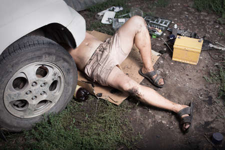 Mechanic lying and working under carの写真素材