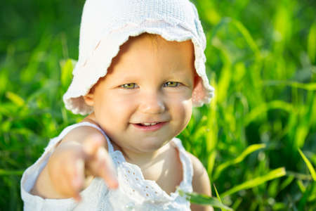 Little girl sitting in the green grassの写真素材