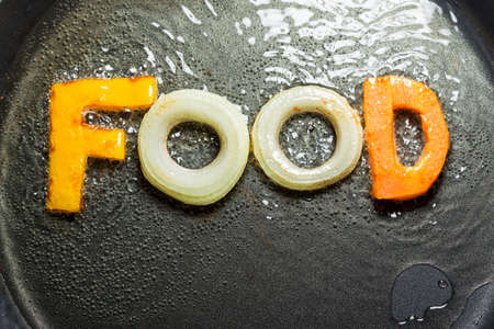 fried vegetables in the form of letters on a frying pan in oilの写真素材