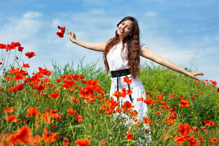 Girl walks in a field of poppiesの写真素材