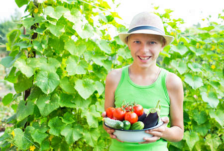 A boy with a bowl of vegetables in the gardenの写真素材