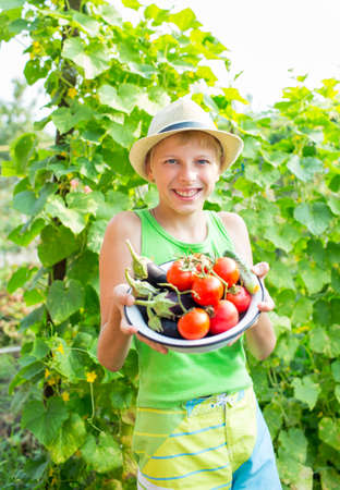 A boy with a bowl of vegetables in the gardenの写真素材