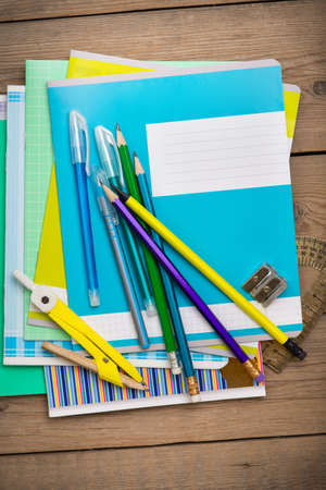 A pack of notebooks for school lies on the old wooden table