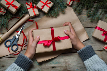 Hands holding Christmas present on the tableの写真素材