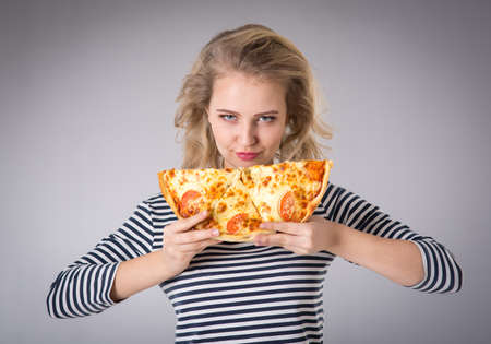 Young woman with a piece of pizza in his handの写真素材