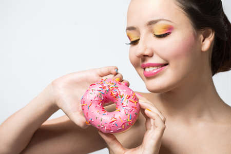 young woman with a pink donut and bright makeupの写真素材