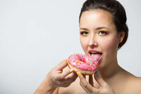 young woman with a pink donut and bright makeupの写真素材