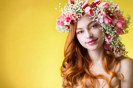 young woman with red hair wearing a wreath of tulipsの写真素材