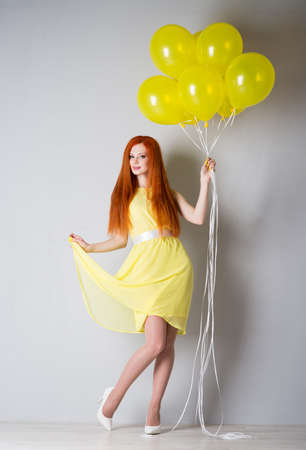 Young woman in a yellow dress with balloonsの写真素材