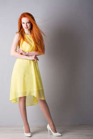 Young woman with red hair in a yellow dressの写真素材