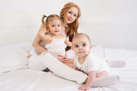 Mother playing with children on the bedの写真素材