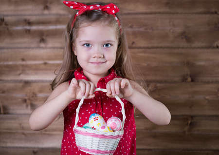 Little girl with Easter eggs on the background of wooden wallの写真素材
