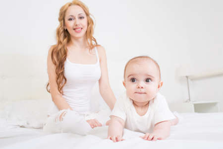 Mother playing with baby on the bed