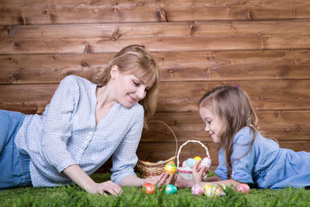 Mother and daughter with easter eggs on the grass