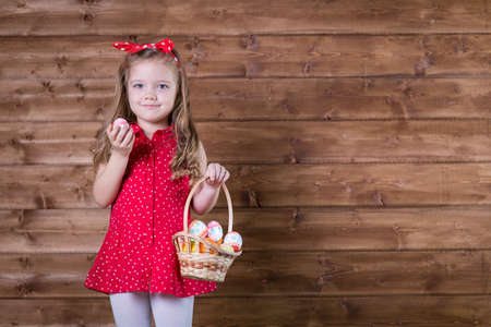 Little girl with Easter eggs on the background of wooden wallの写真素材