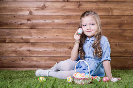 Little girl with Easter eggs on the background of wooden wallの写真素材