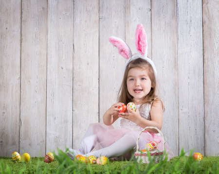 Little girl with Easter eggs on the background of wooden wall