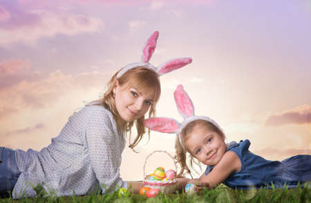 Mother and daughter with easter eggs on the grassの写真素材
