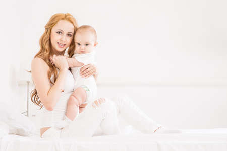 Mother playing with baby on the bedの写真素材