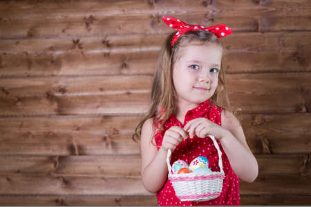 Little girl with Easter eggs on the background of wooden wallの写真素材
