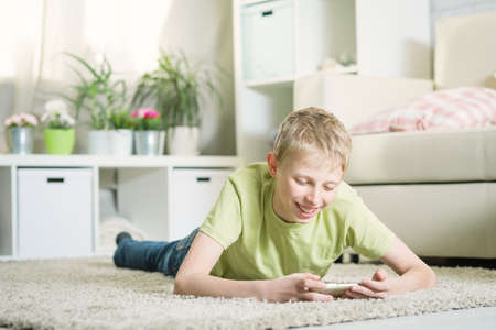 Teen playing phone in the roomの写真素材