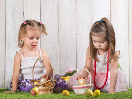 Two babes collect Easter eggs in a basket