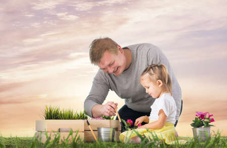 Dad and daughter are thrown flowers in potsの写真素材