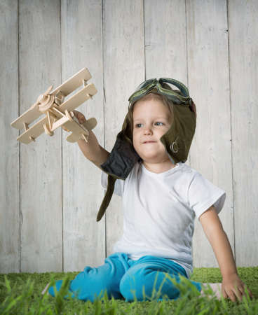 Boy in helmet pilot playing with a model airplaneの写真素材