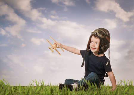 Boy in helmet pilot playing with a model airplaneの写真素材