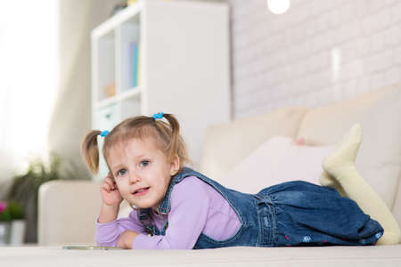 Little girl is playing with the phone in the roomの写真素材