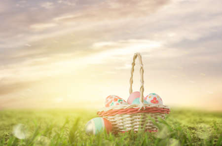 basket with Easter eggs on the grass at sunsetの写真素材
