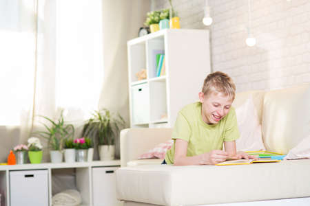 A teenager is reading a book in a roomの写真素材