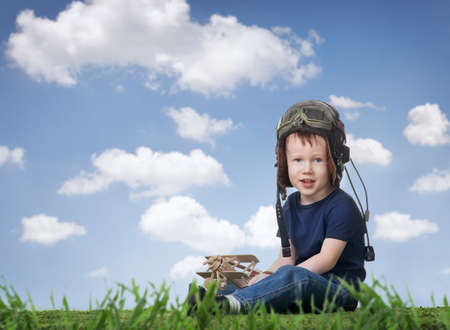 Boy in helmet pilot playing with a model airplaneの写真素材