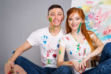 The guy and the girl draw paints on the easel