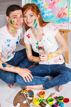 The guy and the girl draw paints on the easel