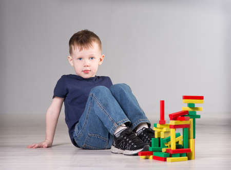 Boy playing with wooden cubes on the floorの写真素材