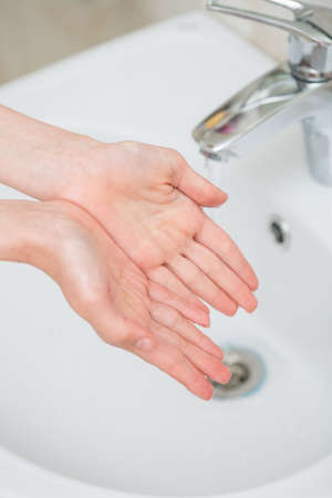 The boy is washing his hands in the bathroomの写真素材