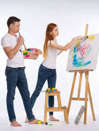 The guy and the girl draw paints on the easelの写真素材