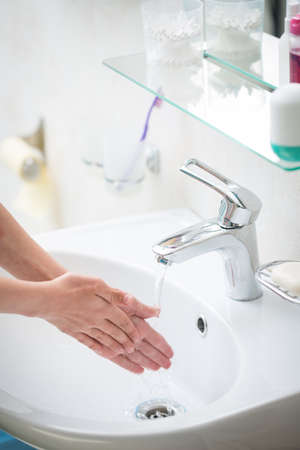 The boy is washing his hands in the bathroomの写真素材
