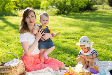 Young woman resting in the park with children, family at a picnicの写真素材