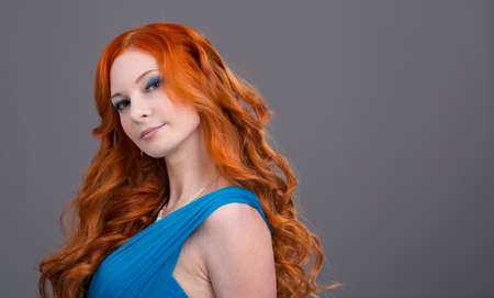 Young woman with long red hair in a blue dressの写真素材