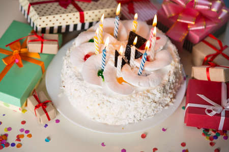 Birthday cake with candles on the table with gifts