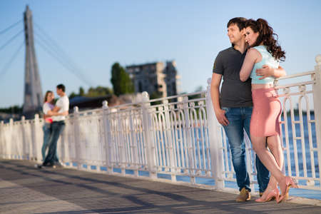 Beautiful young couple sitting on the river bank at sunsetの写真素材