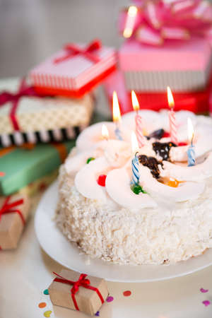 Birthday cake with candles on the table with gifts