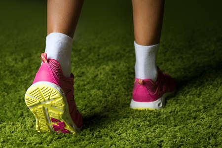 Pink sneakers on the legs of a woman on the grass