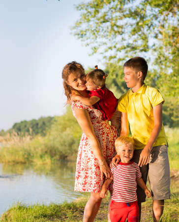Mom with children twins on the river bankの写真素材
